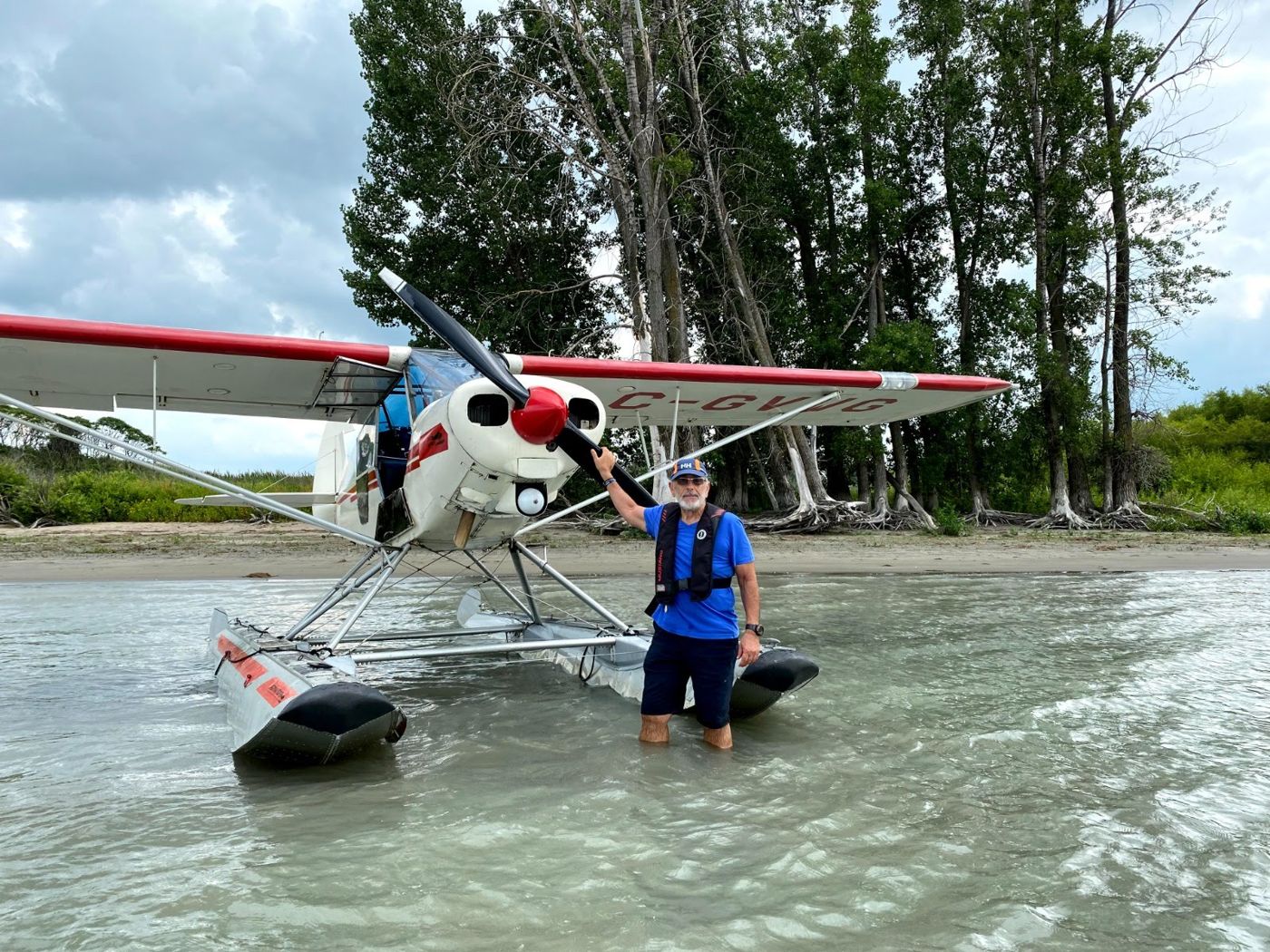 Bashar beside a red and white floatplane in shallow water near Montreal, Canada