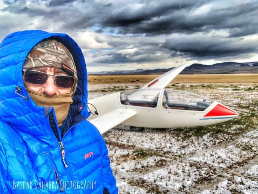 Bashar in winter gear beside a glider on a snowy field